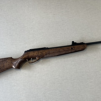 Espingarda com coronha de madeira e cano metálico preto sobre superfície clara