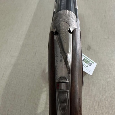 Espingarda double barrel com coronha em madeira e detalhes metálicos gravados