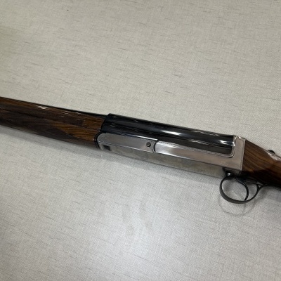 Espingarda com coronha de madeira castanha e partes metálicas em fundo cinza