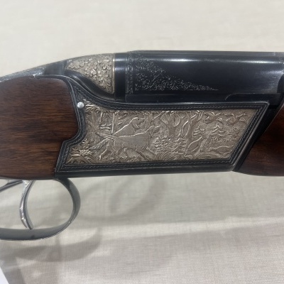 Arma de caça com detalhes gravados em metal e coronha de madeira