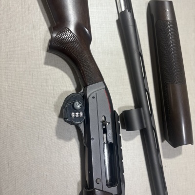 Espingarda de caça desmontada com coronha em madeira escura e cano em metal preto fosco