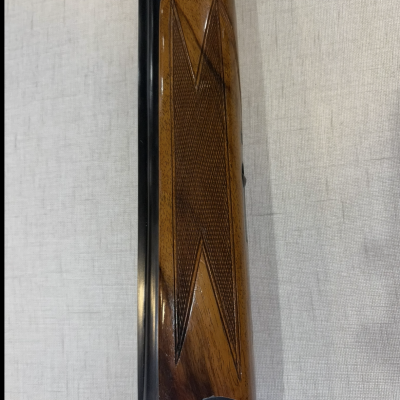 Parte da arma de fogo com empunhadura em madeira e detalhes em metal prateado