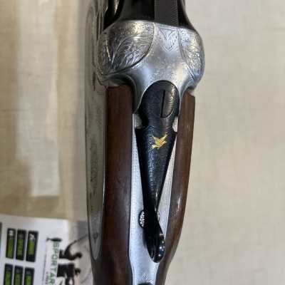 Rifle com madeira castanha e detalhes metálicos gravados, com detalhe dourado de ave