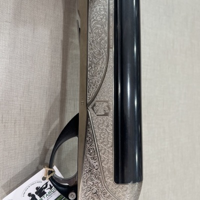 Arma de fogo com caixa metálica gravada e cano escuro com etiqueta pendurada