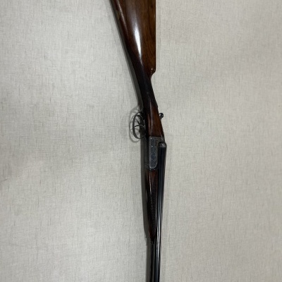 Espingarda de cano duplo com madeira castanha sobre fundo claro