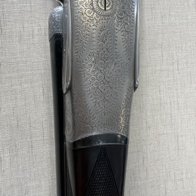 Parte central gravada de uma espingarda de cano duplo com madeira preta texturizada