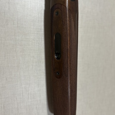 Espingarda com cabo de madeira castanha trabalhada e peças metálicas pretas