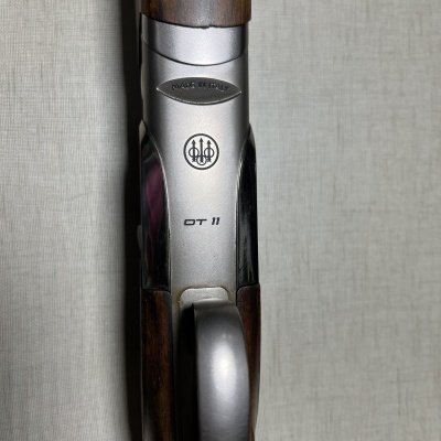 Detalhe da parte superior de uma arma de caça com marcações e cabo em madeira.