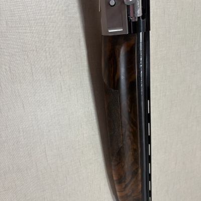 Espingarda com revestimento em madeira escura e metal contra parede clara