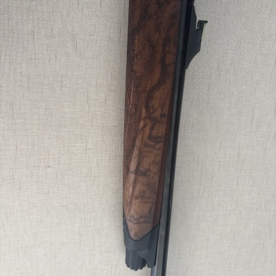 Parte frontal de uma arma de fogo com cabo em madeira castanha e metal prateado