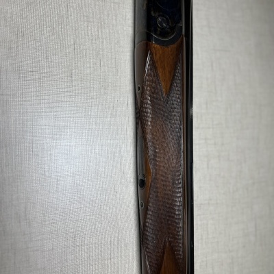 Punho de espingarda em madeira e metal sobre fundo claro