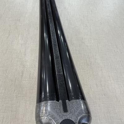 Canos duplex de arma de fogo em metal prateado gravado com canos pretos lushtrosos sobre tecido bege