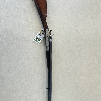 Espingarda de caça de canos duplos com coronha de madeira e partes metálicas prateadas