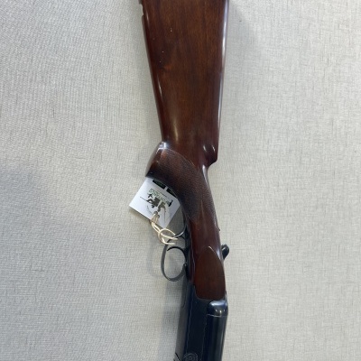 Espingarda com coronha de madeira e cano metálico em fundo claro.