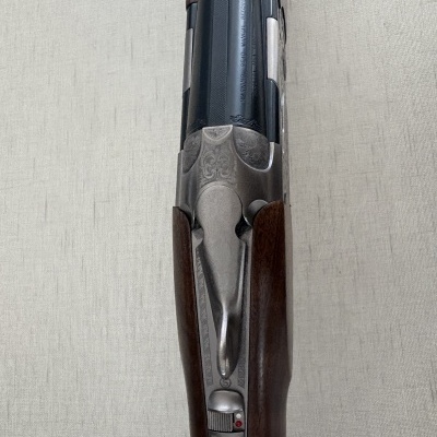 Espingarda de caça com madeira e metal, texto gravado, sobre fundo cinza