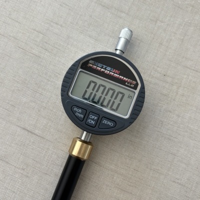Instrumento de medição digital com display LCD e botões sobre superfície cinza texturada