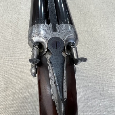 Espingarda de canos duplos com detalhes gravados em metal e madeira escura