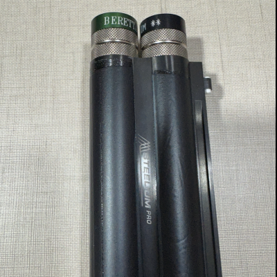 Dois tubos pretos com tampas metálicas e texto BERETTA e M **