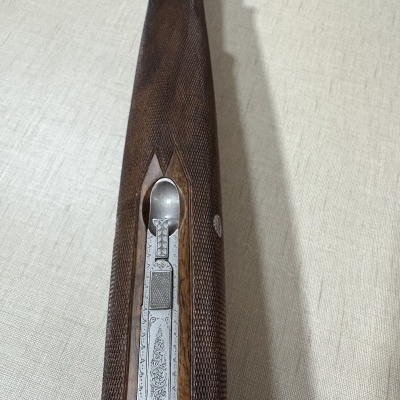 Espingarda com coronha em madeira castanha e detalhes metálicos gravados.