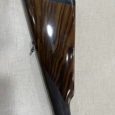 Parte traseira de arma com acabamento em madeira e detalhe em preto