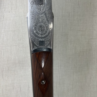 Espingarda de madeira com detalhes de metal gravado e padrão xadrez na coronha