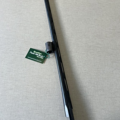 Barra metálica preta com suporte fixador e etiqueta verde sobre superfície cinzenta