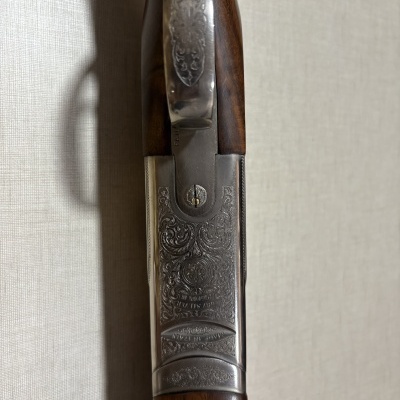 Parte superior de espingarda com madeira e metal gravado.