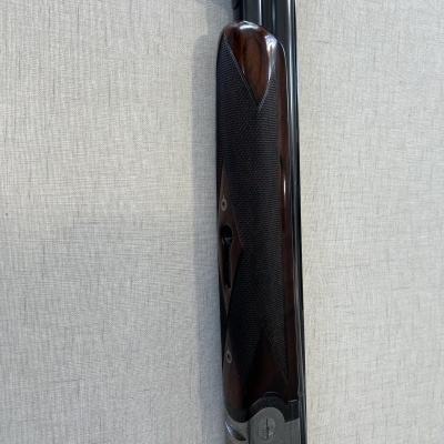 Parte de arma de canos duplos com coronha em madeira escura e canos metálicos