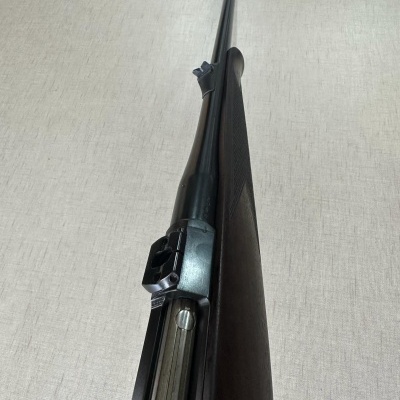 Rifle com coronha de madeira e cano metálico sobre fundo claro