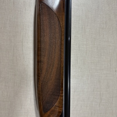 Close-up de parte de espingarda com coronha de madeira e cano metálico preto