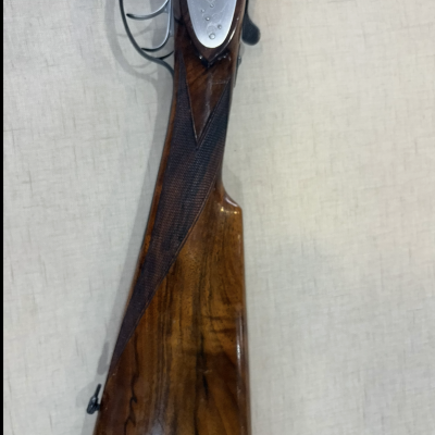 Espingarda de caça com coronha em madeira castanha e detalhes metálicos.