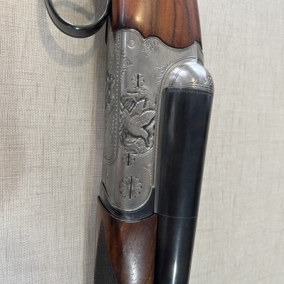 Espingarda de canos duplos com madeira castanha e detalhes metálicos gravados