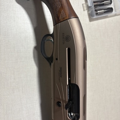 Espingarda com punho em madeira e corpo metálico cinzento com inscrições visíveis BERETTA e XPLOR ACTION.