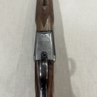 Arma de fogo com empunhadura de madeira e corpo metálico com gravações