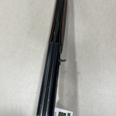 Arma de fogo longa com cano preto e coronha de madeira sobre superfície cinza