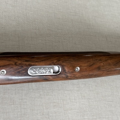 Parte de uma arma de fogo com madeira escura e placa metálica decorativa