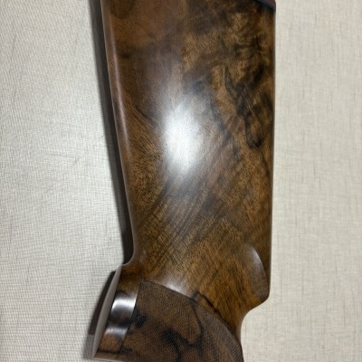 Parte traseira de coronha de arma de madeira polida com bucha vermelha e textura na empunhadura