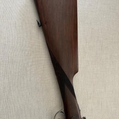 Espingarda de caça com coronha em madeira escura e resguardo vermelho e preto