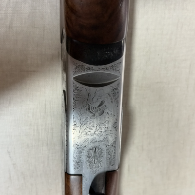 Espingarda com madeira castanha e metal gravado com pássaro e texto P. Beretta
