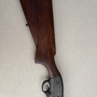 Empunhadura e parte traseira de uma arma de fogo em madeira e metal com inscrições BERETTA, Xplor Unico.