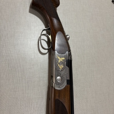 Espingarda Beretta em madeira escura e metal prateado com gravações douradas