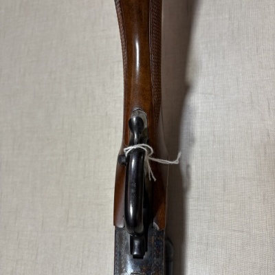 Espingarda de cabo de madeira castanha e armação metálica detalhada sobre tecido bege