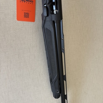 Arma de fogo preta com etiqueta laranja PX800 SUPREMA sobre fundo bege.