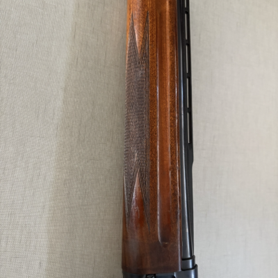 Parte dianteira de arma de fogo com madeira castanha e metal preto.