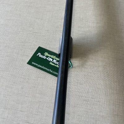 Vara de pesca preta sobre superfície bege com cartão verde ao lado