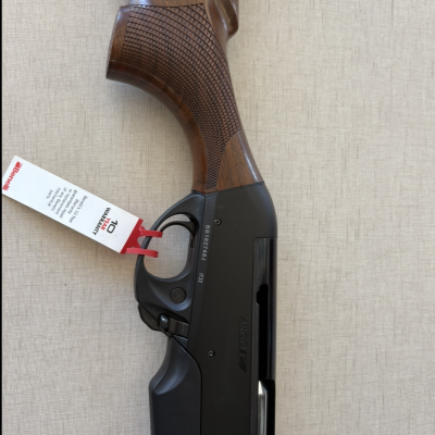 Espingarda com coronha em madeira trabalhada e corpo preto com etiqueta Benelli