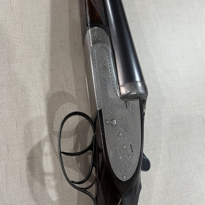 Espingarda de canos duplos com madeira escura e detalhes metálicos