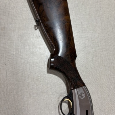 Parte traseira e alça de espingarda em madeira escura e metal cinzento com gatilho dourado