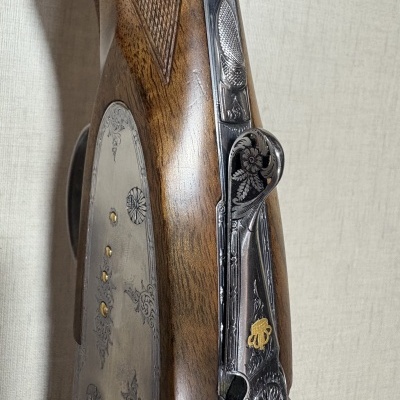 Close-up de uma espingarda com detalhes em madeira e metal gravado