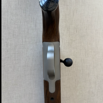 Parte inferior de arma de madeira com metal prateado e botão negro